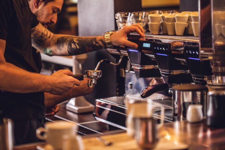 Man preparing coffee at table in cafe